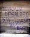 The metal door protecting a storefront with a slogan, in Spanish, painted on it